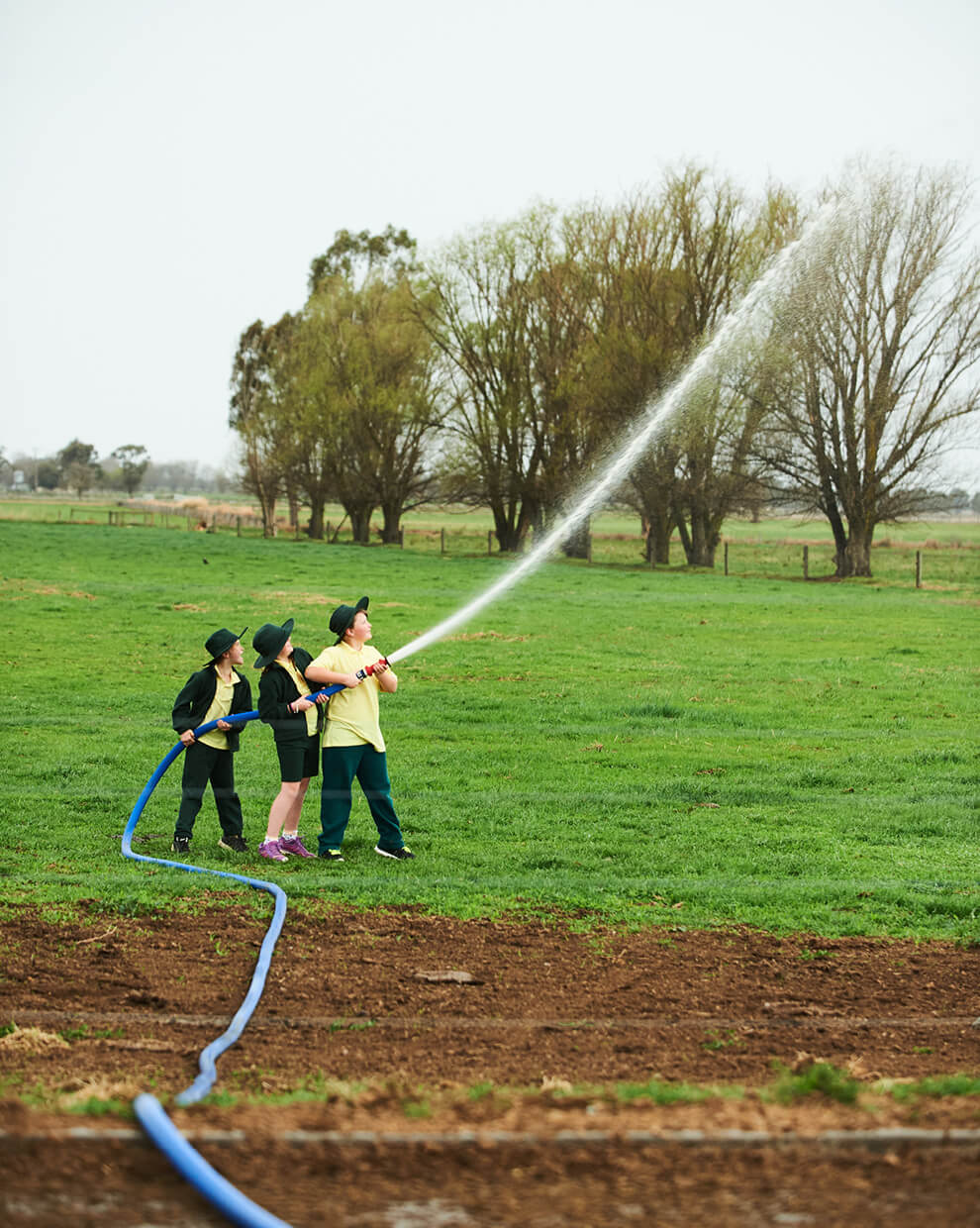Jalna kids holding fire hose spraying water