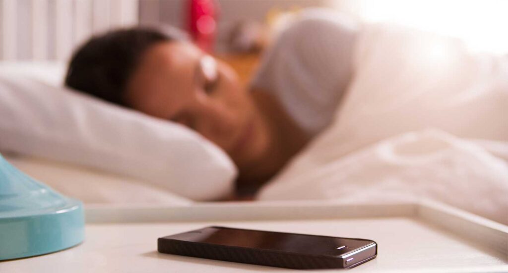 Woman sleeping with phone on bedside table