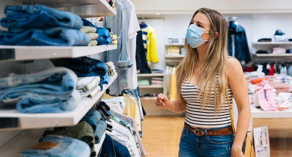 Woman with hygiene mask on shopping for denim in store
