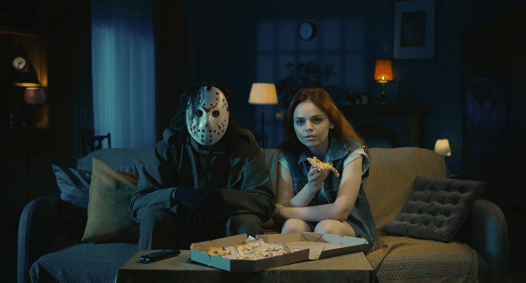 Man with mask and girl eating pizza on couch